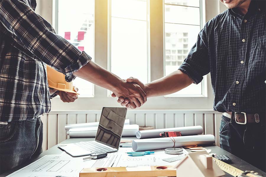Specialized Business Insurance - Contractor And Client Shaking Hands In Office Over Desk With Building Plans